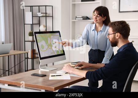 Kartografen arbeiten mit Katasterkarten am Computer am Tisch im Büro Stockfoto