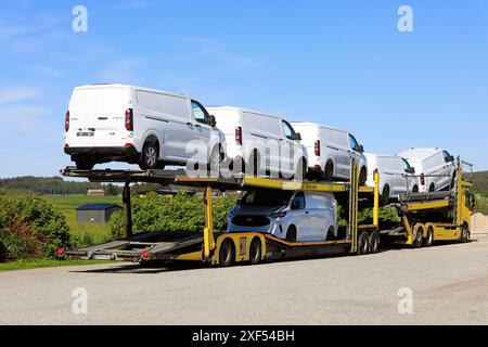 Der gelbe Volvo Fahrzeugträger transportiert sechs neue, weiße Ford Transit Custom Transporter auf Anhänger, Rückansicht. Salo, Finnland. Juni 2024. Stockfoto