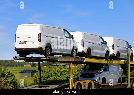 Der Lkw transportiert neue, weiße Ford Transit Custom Transporter auf einem Anhänger. Detail der Rückansicht. Salo, Finnland. Juni 2024. Stockfoto