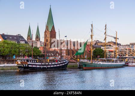 Die Schlachte ist Bremens maritime Meile an der Weser. Besucher finden Cafés, Restaurants und Bars in den ehemaligen Lagerhäusern entlang des Kais, wo Ausflugsdampfer und Restaurantschiffe aufgereiht liegen. Die Segelschiffe „Admiral Nelson“ und „Alexander von Humboldt“ liegen an der Weser vor den Türmen des St. Petri Dom und der St. Martini Kirche festgemacht. Bremen, Deutschland. Stockfoto