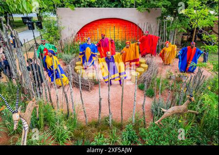 London, Großbritannien. Juli 2024. The Lion King Anniversary Show Garden, bildet das Set als Star von Disney's The Lion King in the West End, Thenjiwe Nofemele und andere Mitglieder der Besetzung führen den ikonischen „Circle of Life“ in ihrem vollen Rafiki-Kostüm auf, begleitet vom 25. Jahr der Show im Lyceum Theatre. - Das 2024 RHS Hampton Court Palace Garden Festival. Guy Bell/Alamy Live News Stockfoto