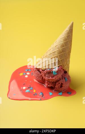 Geschmolzenes Eis in Waffelkegel auf gelbem Hintergrund Stockfoto