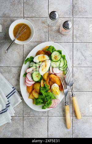 Salat mit gebratenen Babykartoffeln, weich gekochtem Ei, Rettichgurke und Hollandaise-Sauce auf alten alten Fliesen Tischhintergrund, Draufsicht, Kopierraum Stockfoto