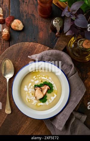 Cremesuppe mit Stachelpilzen gemütliche Atmosphäre auf rustikalem Holzküchentisch mit Schneidebrett, Zutaten und Küchenutensilien. Herbsternte Stockfoto