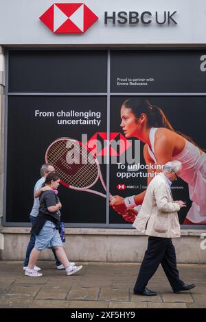 Wimbledon, London, Großbritannien 1. Juli 2024. Fußgänger gehen an einer lokalen Filiale der HSBC Bank im Stadtzentrum von Wimbledon vorbei und sehen ein Bild der britischen Tennisspielerin Emma Raducanu als globale Markenbotschafterin. Quelle: Amer Ghazzal/Alamy Live News Stockfoto