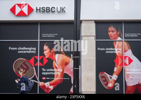 Wimbledon, London, Großbritannien 1. Juli 2024. Ein Fußgänger läuft an einer lokalen Filiale der HSBC Bank im Stadtzentrum von Wimbledon vorbei. Mit einem Bild der britischen Tennisspielerin Emma Raducanu als globale Markenbotschafterin. Quelle: Amer Ghazzal/Alamy Live News Stockfoto