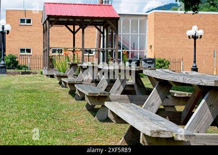 Vier abgenutzte und verzerrte Picknicktische in einem kleinen Park mit Pavillon Stockfoto