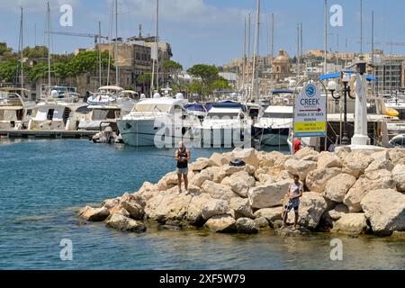 Valletta, Malta - 3. August 2023: Menschen fischen von Felsen am Eingang zu einem der Häfen in Valletta Stockfoto