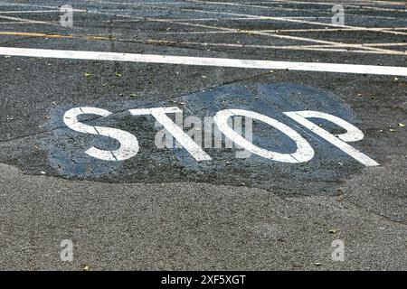 Stoppschild auf dem Asphalt des Parkplatzes in der Stadt gemalt. Das Stoppschild hat ein schwarz-weißes Design Stockfoto