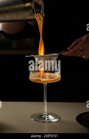 Barista gießt Eiskaffee aus der Kanne ins Glas. Nur Hände. Stockfoto