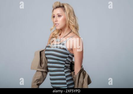 Schönes Model in einem gestreiften modischen Kleid, zeigt ihre Posen-Fähigkeiten in diesem Studio-Foto, trägt eine Halskette dieses Bild ist für Mode geeignet Stockfoto