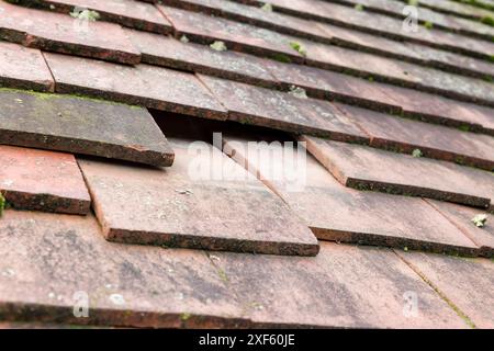 Fehlende und rutschte glatte Dachziegel auf einem geneigten Dach eines alten Hauses in England, Großbritannien Stockfoto