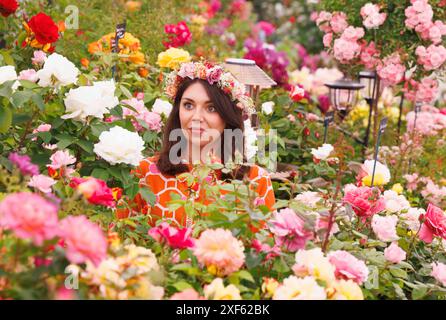 London, Großbritannien. Juli 2024. Eine Frau posiert zwischen den Rosen mit einer Blumengirlande auf dem Kopf. Pressetag auf der RHS Hampton Court Flower Show. Quelle: Mark Thomas/Alamy Live News Stockfoto