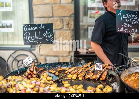 Lebhafte Szene eines Freiluftmarktes in Vannes, Bretagne, Frankreich, auf dem verschiedene Gerichte wie Hühnchen, Würstchen und Kartoffeln angeboten werden. Stockfoto
