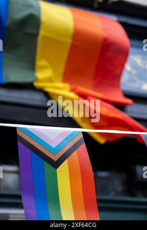 Stolz-Progress-Flagge und Regenbogenflagge in Soho am 30. Juni 2024 in London, Großbritannien. Die Flagge enthält die Regenbogenflaggenstreifen, die LGBTQ+-Gemeinschaften repräsentieren, mit Farben aus der Transgender Pride Flag und auch farbige Menschen repräsentieren. Stockfoto