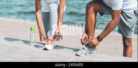 Afro Paar Schnürung Schuhe Neben River Embankment, 7/8 Stockfoto