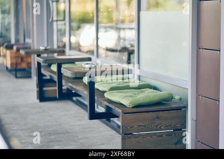 Tische mit Sofas und auf der Straße vor dem Hintergrund von Fenstern. Ein Café im Freien in der Stadt. Der Bodenbelag besteht aus Beton auf dem Boden mit Platz zum Kopieren. Hochwertige Fotos Stockfoto