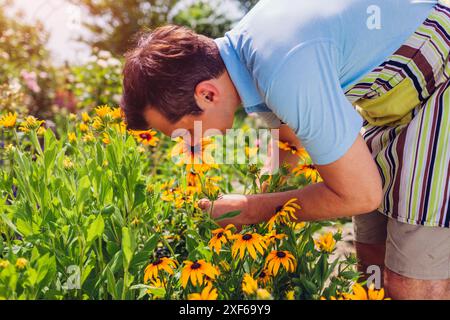 Porträt eines jungen Mannes, der im Sommergarten Rudbeckia-Blumen pflückt. Gärtner riecht nach gelben Blüten. Lifestyle Stockfoto