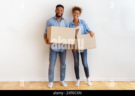 Ehegatten Holding Umzugskisten Gegen die Wand im neuen Haus stehend Stockfoto