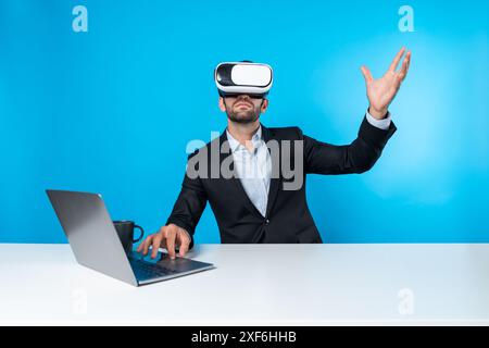 Erfahrener Geschäftsmann, der Datenanalysen ansieht, während er mit Laptop am Tisch sitzt und eine VR-Brille trägt. Projektmanager arbeitet mit Virtual Real Stockfoto