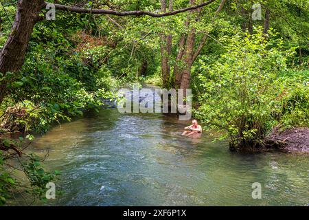 Ein Mitglied der Bowbridge Baders kühlt sich an einem heißen Sommertag im River Frome bei Bowbridge in den Stroud Valleys, Gloucestershire, England, ab Stockfoto