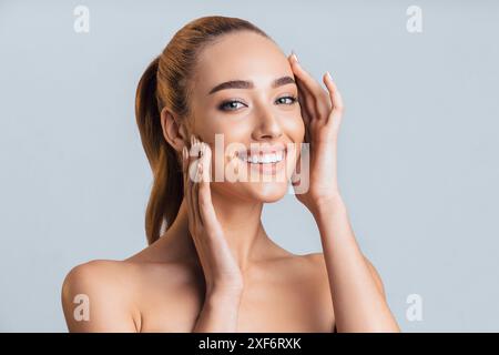 Eine Junge Frau Lächelt Im Studio Mit Händen Auf Dem Gesicht Stockfoto