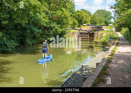 Ein Paddleboarder nähert sich Ryeford Double Lock auf der Stroudwater Navigation bei Ryeford bei Stonehouse in den Stroud Valleys, Gloucestershire, Großbritannien Stockfoto