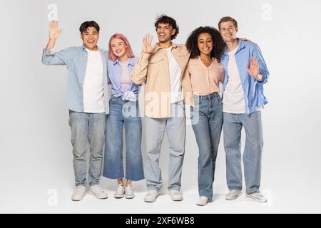 Eine Gruppe verschiedener Freunde lächelt und winkt im Studio Stockfoto