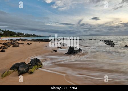 USA, Hawaii, Maui. Keawakapu Beach und der weiße Sand und die Wellenbewegung über Lavafelsen Abendlicht Stockfoto