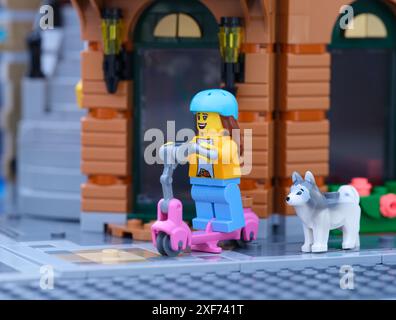 Tambow, Russische Föderation – 30. Juni 2024 Eine Lego-Girl-Minifigur, die mit ihrem Hund auf einem Roller die Straße entlang fährt Stockfoto