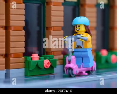 Tambow, Russische Föderation - 30. Juni 2024 Eine Lego-Girl-Minifigur, die auf einem Roller eine Stadtstraße hinunterfährt Stockfoto