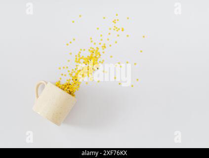Kreatives Layout mit Kaffeetasse und Konfetti mit goldenen Glitzersternen auf weißem Hintergrund. Festliche Feiertage. Minimales Konzept für Kaffeepartys. Stockfoto