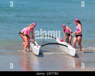 Tauranga Neuseeland - 28. Januar 2012; Frauen in rosa Streifen Surf Kanu Paddler lassen Wasser in Surf Club Event. Stockfoto