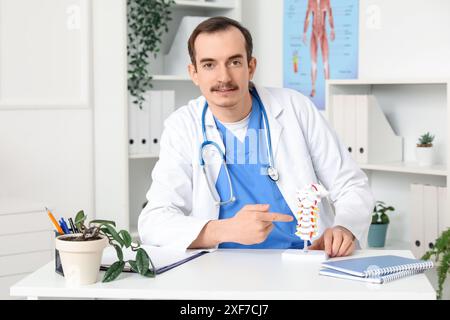 Männlicher Arzt mit Wirbelsäulenmodell in der Klinik Stockfoto