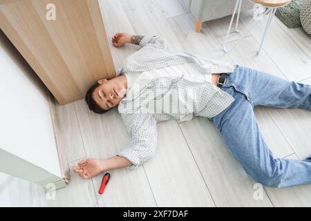 Ein junger Mann mit Stromschlag in der Nähe der Steckdose zu Hause Stockfoto