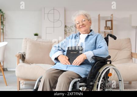 Ältere Frau im Rollstuhl mit Bibel zu Hause Stockfoto