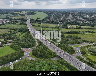 Ein Blick aus der Vogelperspektive auf einen stark frequentierten Autobahnkreuz der Autobahn A41 M25 in London, England, umgeben von grünen Feldern und Wohngebieten Stockfoto