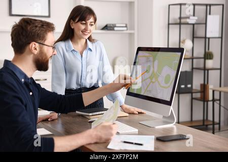Kartografen arbeiten mit Katasterkarten am Computer am Tisch im Büro Stockfoto