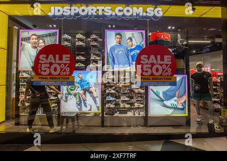 Die Mitarbeiter des Stores tauschen einige Schuhe aus, die im Regal bei JD Sports ausgestellt sind, einem 50-prozentigen Verkaufsaufkleber, um den Umsatz zu steigern und die Schuhe der vergangenen Saison zu entfernen. Singapur. Stockfoto