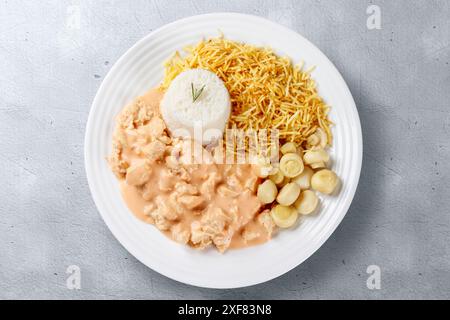 Hausgemachte Hühnerstroganoff in Keramikschale isoliert auf Zementtisch. Draufsicht Stockfoto