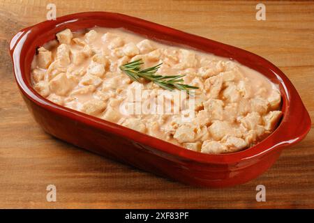 Hausgemachtes Hühnerstroganoff in Keramikschale auf rustikalem Holztisch. Draufsicht Stockfoto