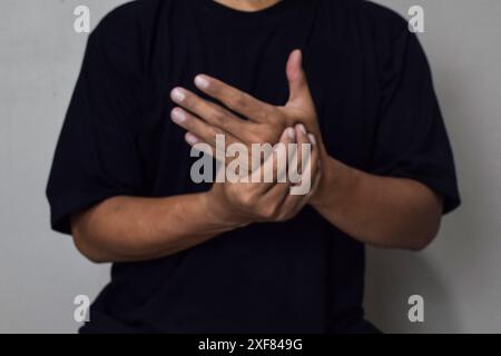 Sicht auf die Männermassage an den Fingern zur Linderung von Schmerzen bei harter Arbeit bei Gicht und rheumatoiden Symptomen und chronischen Erkrankungen mit wenig verschwommener Wirkung Stockfoto