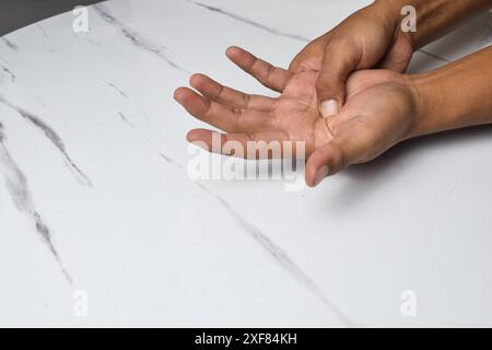 Sicht auf die Männermassage an den Fingern zur Linderung von Schmerzen bei harter Arbeit bei Gicht und rheumatoiden Symptomen und chronischen Erkrankungen mit wenig verschwommener Wirkung Stockfoto