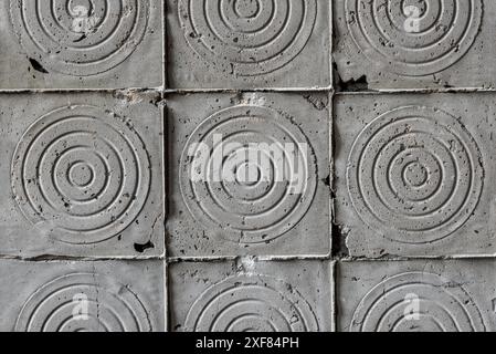 Alte dunkelgraue Betonwandstruktur mit zerbröckelnden quadratischen Fliesen in Nahaufnahme Stockfoto