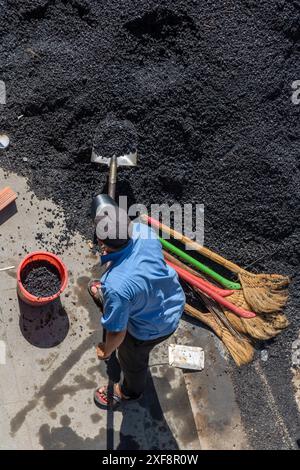 Ein Arbeiter mit einer Schaufel lädt Baumaterial in einen Eimer Stockfoto