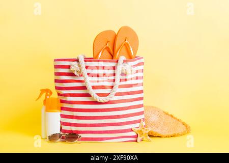 Stilvolle Tasche mit Strandaccessoires. Sommerferienkonzept. Blick von oben auf die Strandtasche mit Sonnencreme und Platz für Text. Stockfoto