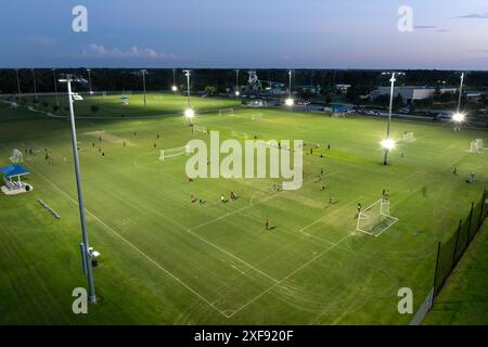 Blick aus der Vogelperspektive auf den öffentlichen Sportpark mit Menschen, die bei Sonnenuntergang im Grasstadion spielen. Aktives Lebenskonzept. Stockfoto