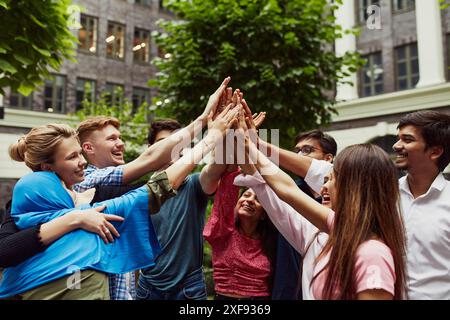 Verschiedene Gruppen von Freunden, die sich gegenseitig unterstützen, Studenten verschiedener Nationalitäten geben High Five und feiern erfolgreiche Prüfungen Stockfoto