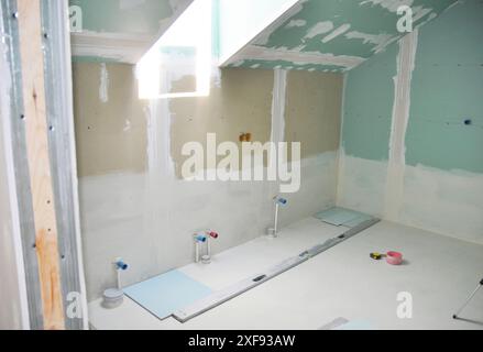 Nahaufnahme auf dem Haus Dachboden Badezimmer Renovierung innen. Dachfenster, Gipskartonwand, wasserdichte Trockenbauwand, Rohrleitung, wasserdichter Boden unter Hauskessel Stockfoto