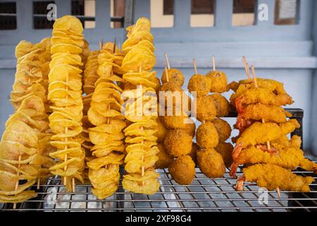 Street Food-Stand, der spiralgeschnittene, frittierte Kartoffelchips auf Spießen verkauft. Frittierte Spieße, asiatisches Streetfood. Frisch gekocht und auf einem Essen ausgestellt Stockfoto